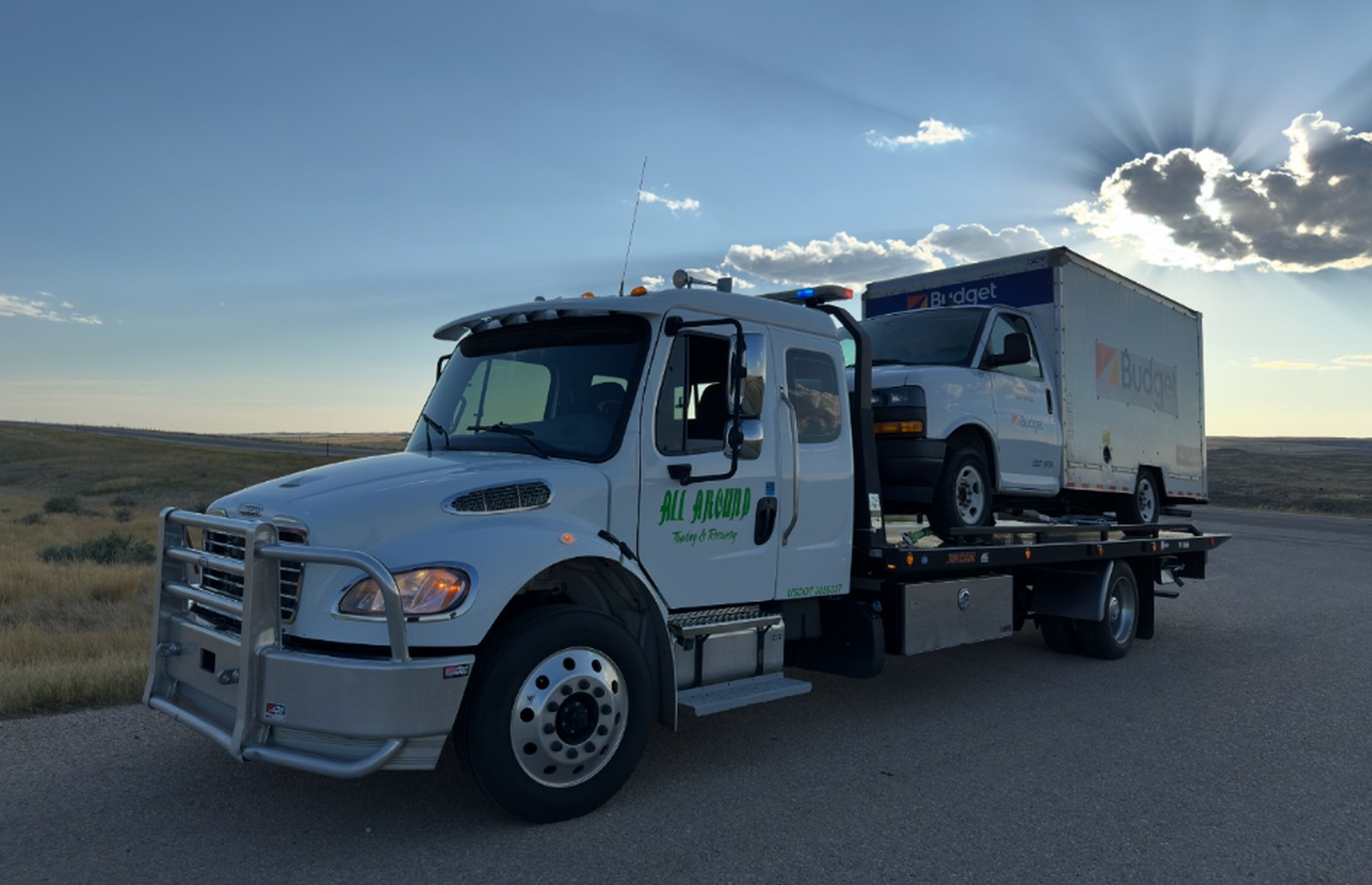 All Around Towing Freightliner M2 106 rollback at sunset with a loaded box truck